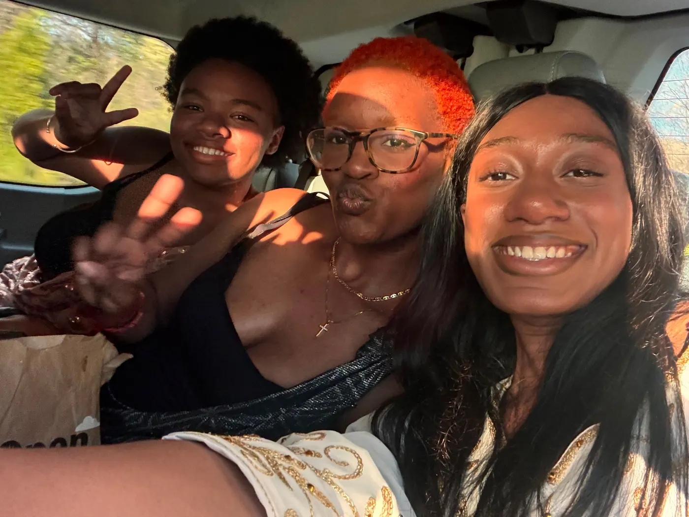 Three students in a car, turned towards the camera.