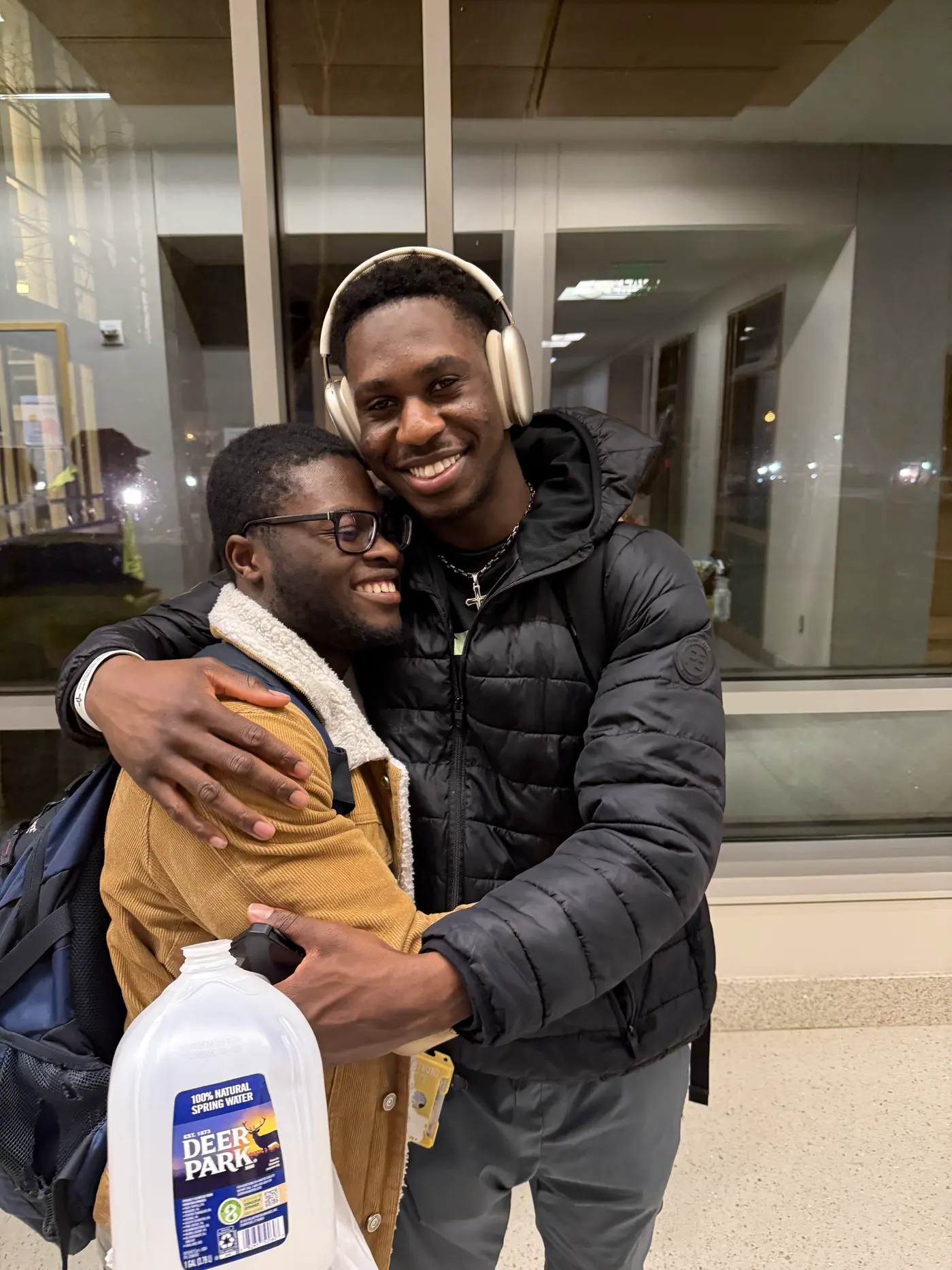 Two students holding on to each other outside a building at night.
