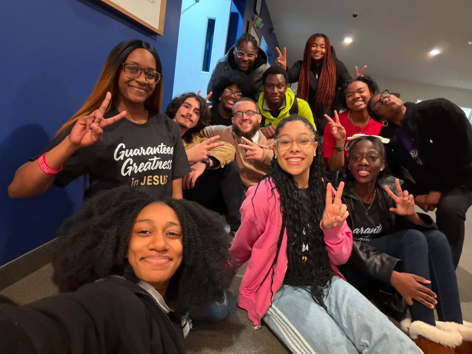 A group of students crowded onto a staircase for a photograph, several making peace signs.