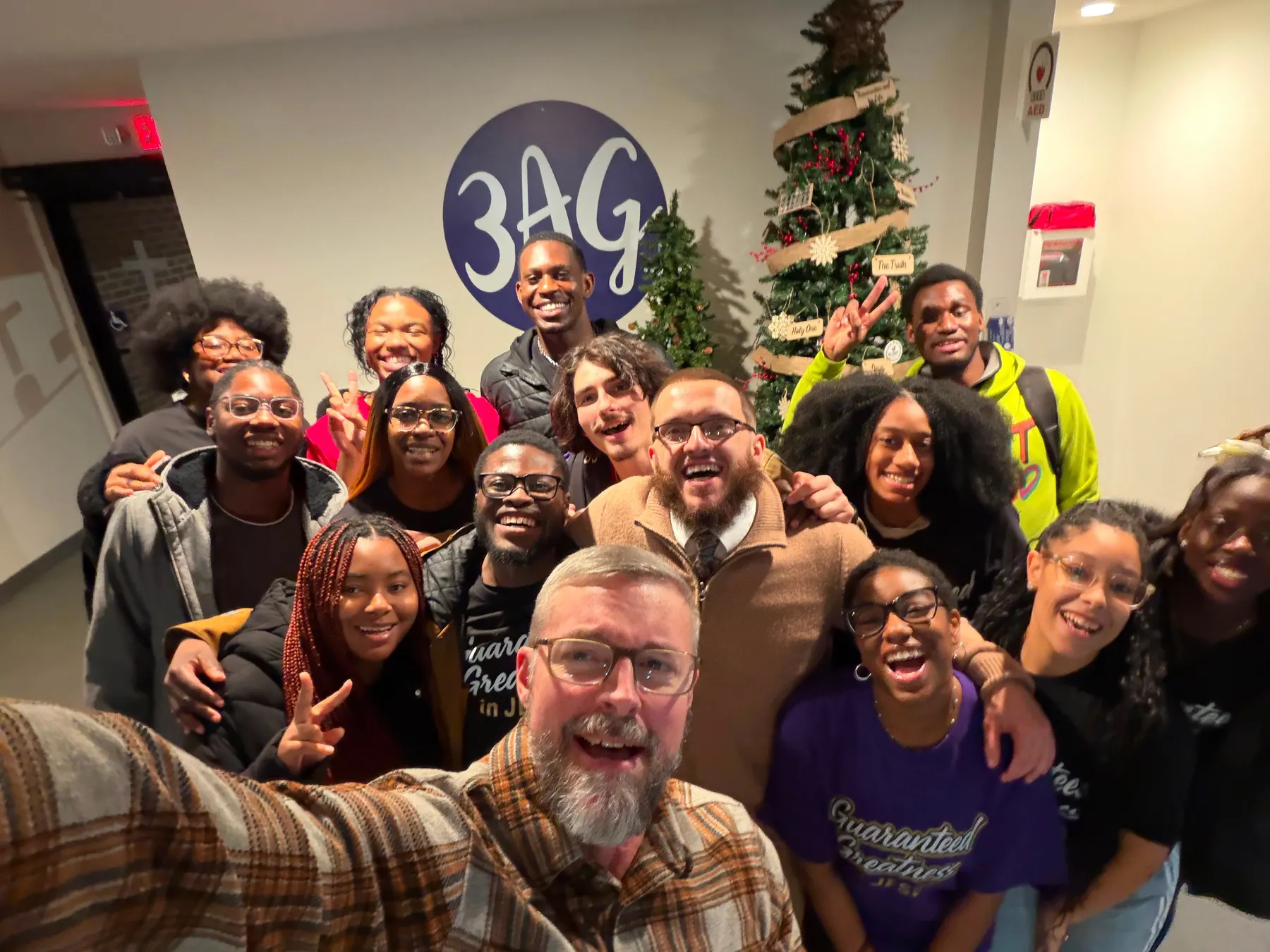 Students crowded together for a photograph beside a decorated Christmas tree.