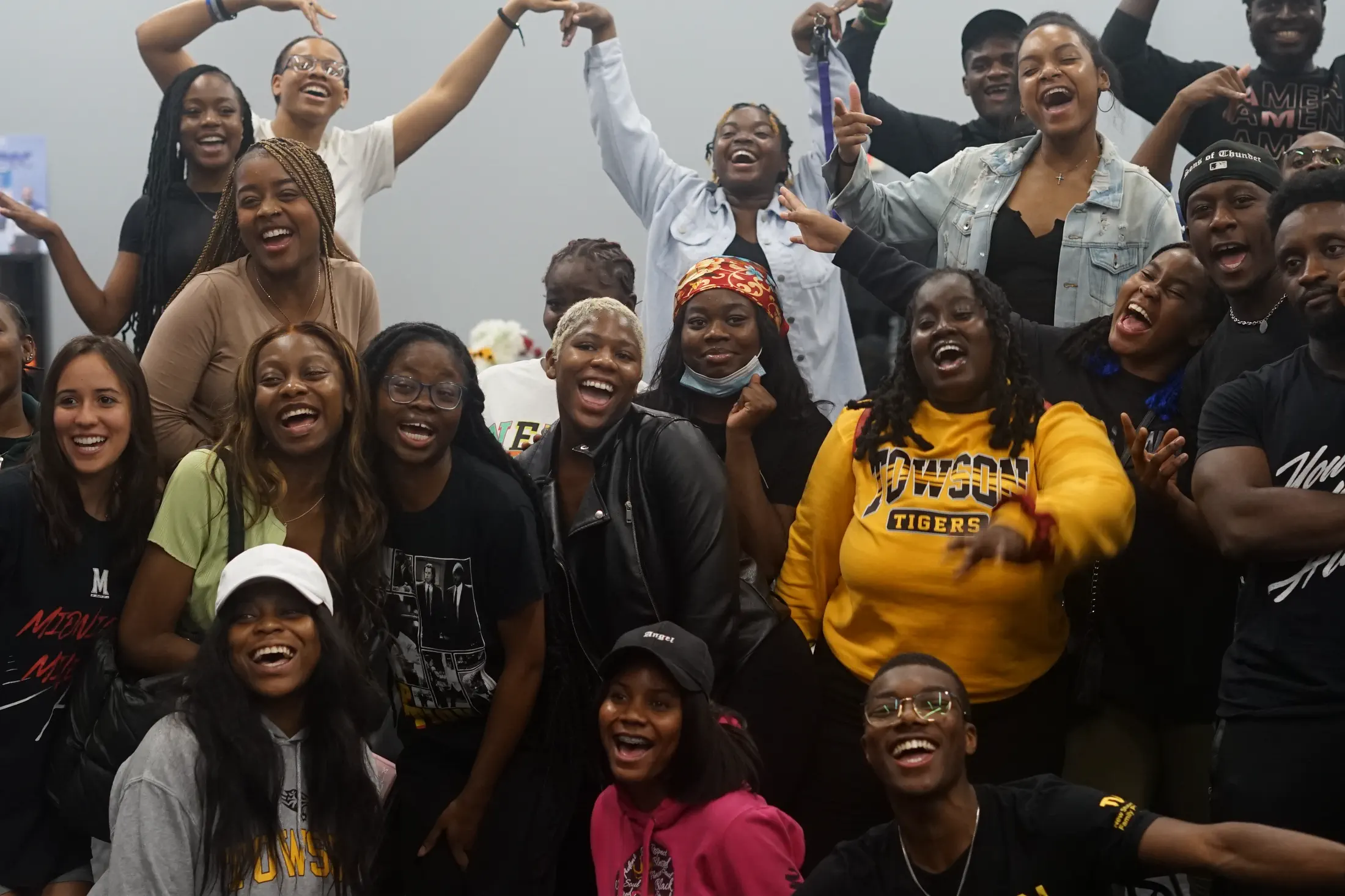 A large group of students crowded together, laughing, at a 100% Triumph gathering.